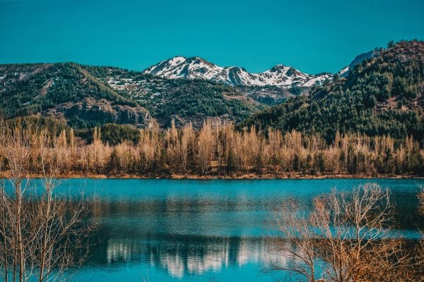 Otoño Dorado: 8 Destinos Espectaculares para una Escapada Inolvidable Un hermoso lago rodeado de un bosque con hojas doradas en otoño y montañas nevadas al fondo, simbolizando una escapada inolvidable.