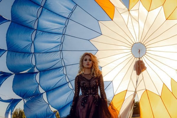 Tendencias de Viajes 2026: Cómo y Dónde Viajaremos en el Año de los Grandes Eventos Mujer con elegante vestido de noche delante de una paracaídas multicolor que ilustra las tendencias de viajes en 2026