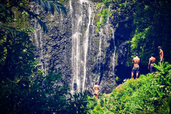 Amazonas: Viaje al Corazón Verde del Planeta Tres personas de espaldas, observando una pequeña cascada en el corazón del Amazonas, una aventura en el pulmón verde del planeta.