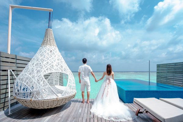 Maldivas para Dos: Creando la Luna de Miel de Lujo Definitiva Una pareja recién casada disfrutando de su luna de miel de lujo en una plataforma sobre el mar de Maldivas.