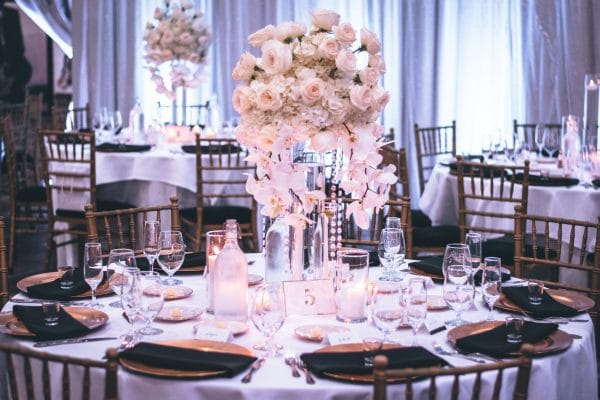 El Presupuesto para tu Luna de Miel: Guía de Costes y Ahorro Mesas redondas decoradas con jarrones de rosas para ilustrar El Presupuesto para tu Luna de Miel: Guía de Costes y Ahorro