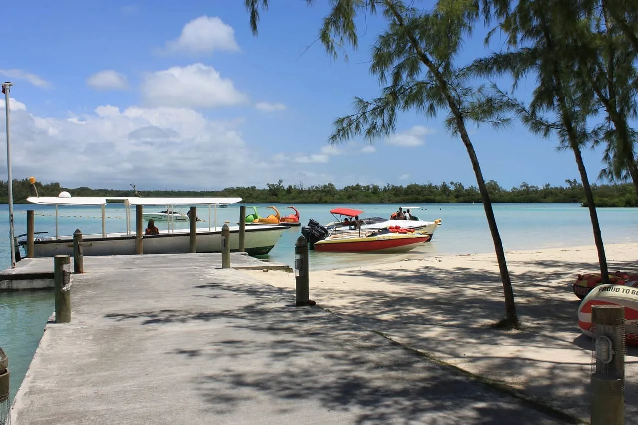 Playa tropical con muelle de madera y lanchas en laguna turquesa de Mauricio para viaje exclusivo