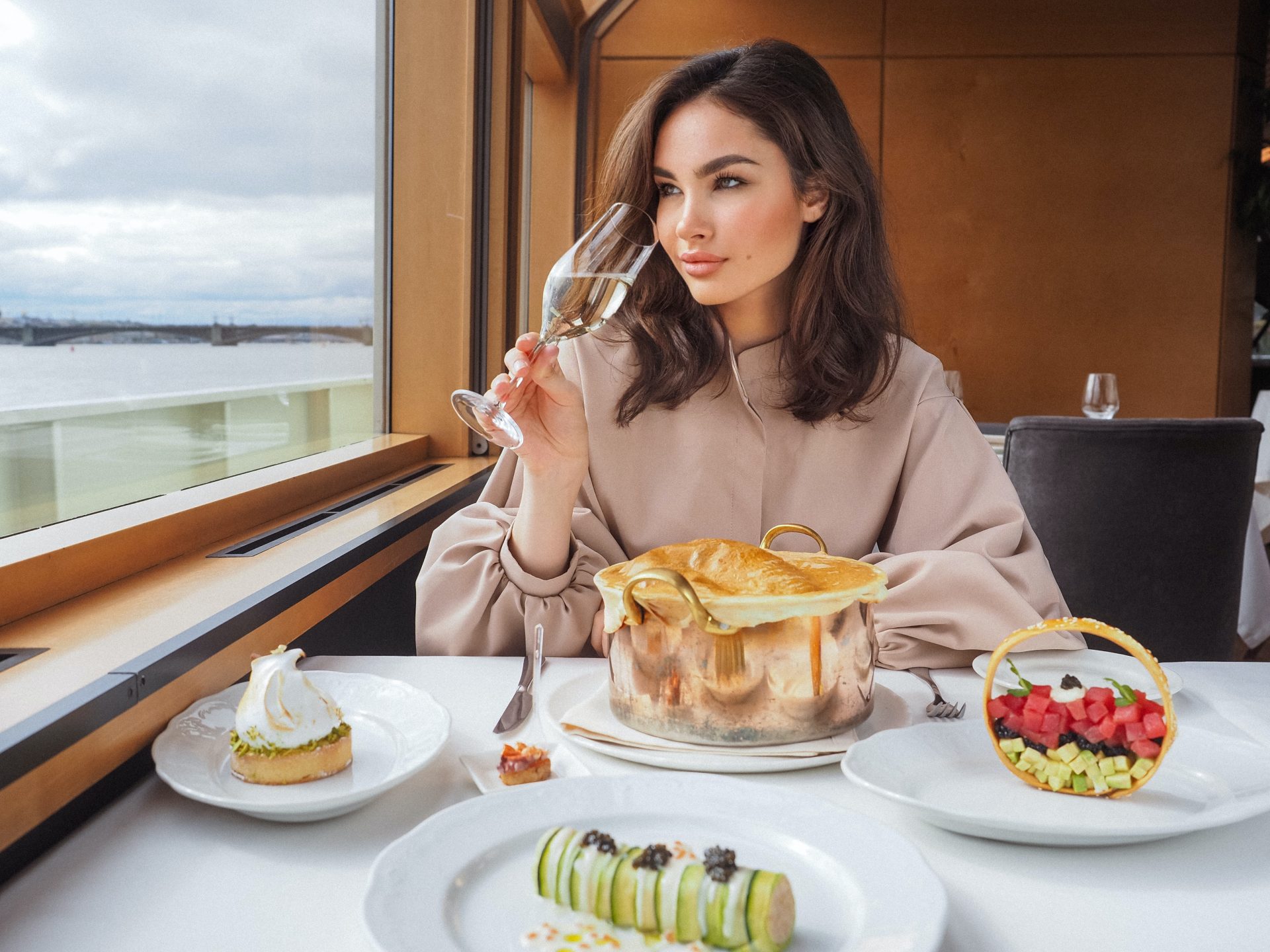 Una mujer elegante disfrutando de una copa de vino en un crucero de lujo, con vistas al mar, representando el estilo de vida que puedes elegir en tu próximo viaje.