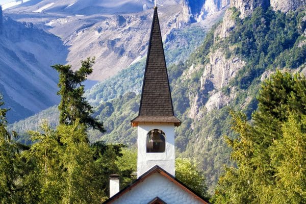 Iglesia solitaria entre las montañas de Bariloche que ilustra el trekking en Argebtina