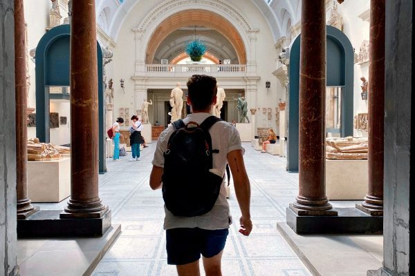Nuevas Fronteras: Expediciones Exclusivas a los Confines del Mundo Un viajero con mochila explorando el patio de un monumento, ilustrando las expediciones a los confines del mundo.