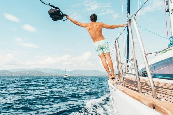 Un joven en bañador en un velero de lujo, representando un crucero todo incluido y el estilo de vida de lujo en el mar.