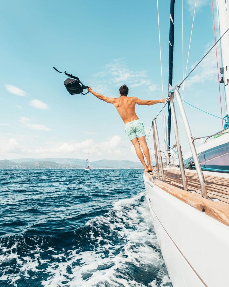 Un joven en bañador en un velero de lujo, representando un crucero todo incluido y el estilo de vida de lujo en el mar.