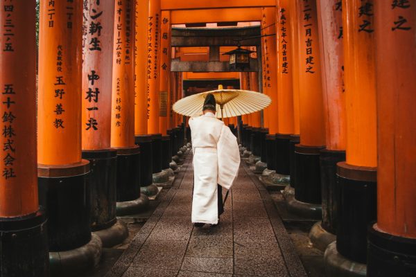 Japón Profundo: Un Itinerario de Lujo de 15 Días para una Inmersión Cultural Auténtica Un hombre con atuendo ceremonial japonés en un camino con escrituras, representando una inmersión cultural auténtica en Japón.