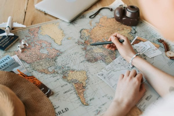 Manos con un bolígrafo sobre un mapa del mundo que ilustra los destinos 2026