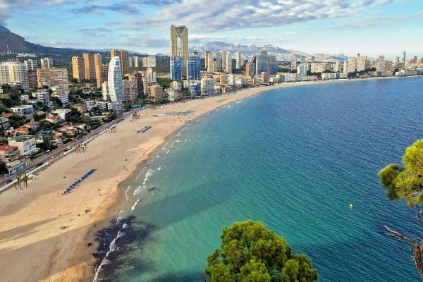 Panorámica de la playa y los edificios de Benidorm, representando las vacaciones en la Costa Blanca y el paraíso mediterráneo.