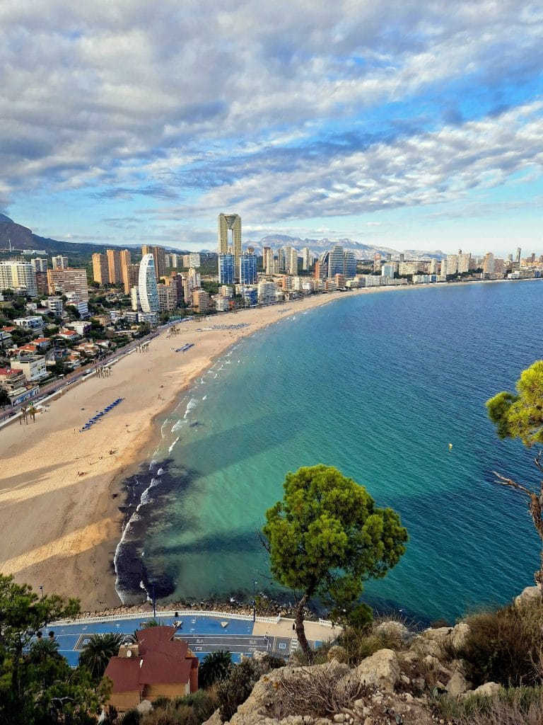 Panorámica de la playa y los edificios de Benidorm, representando las vacaciones en la Costa Blanca y el paraíso mediterráneo.