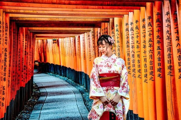 Una mujer en kimono caminando por un pasillo con elementos de escritura japonesa, representando un viaje al corazón de la tradición en Kioto.