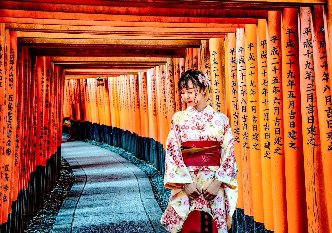Una mujer en kimono caminando por un pasillo con elementos de escritura japonesa, representando un viaje al corazón de la tradición en Kioto.
