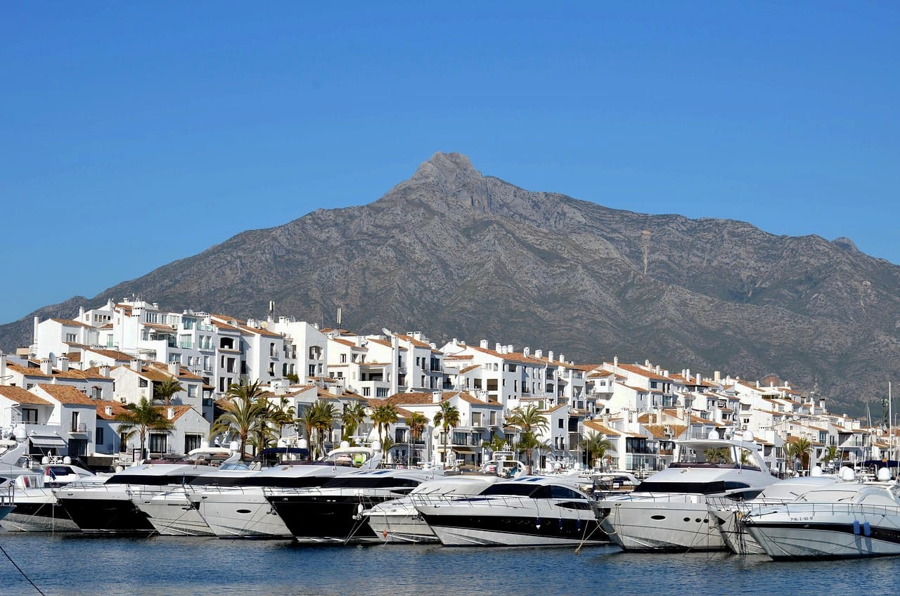 Vista de Puerto Banús desde el mar con la montaña de fondo, representando el itinerario por la exclusiva Marbella.