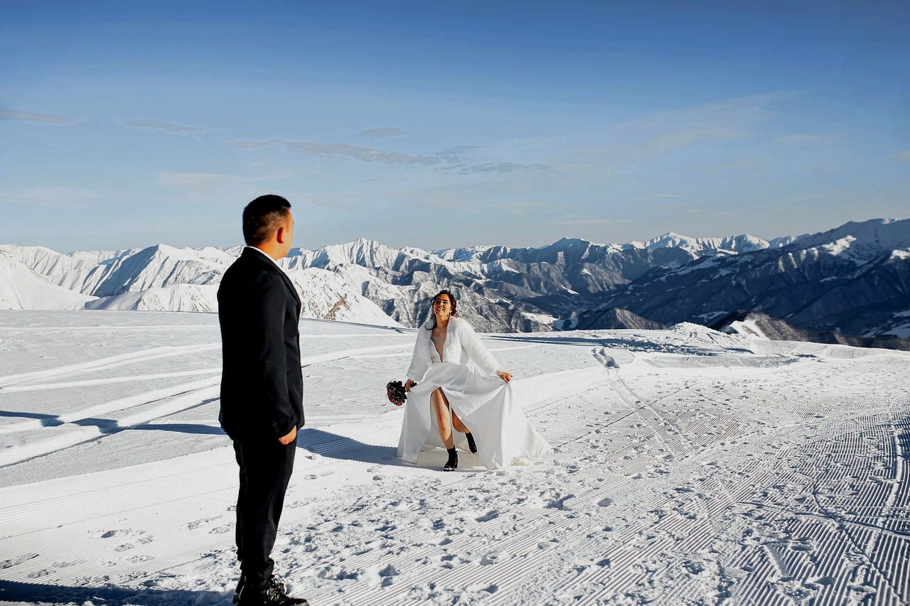 Una pareja de novios en un emocionante momento, con la novia corriendo hacia el novio sobre una montaña nevada en un glaciar.
