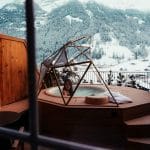 Esquí en los Alpes Suizos: Lo Que No Muestran las Fotos una chica dentro de un jacuzzi en la terraza de un hotel con el fondo de una montaña nevada