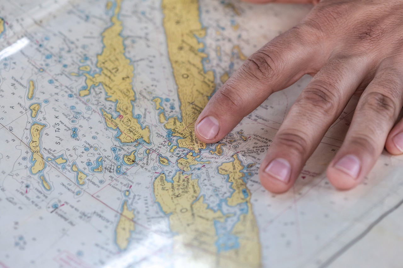 Mano de un concierge planificando estratégicamente una ruta de viaje de lujo a través de un mapa de islas.