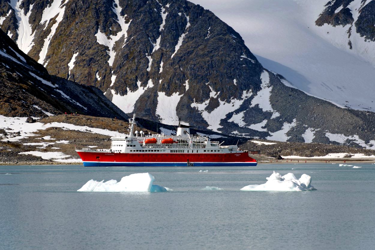 Crucero de expedición de lujo con clasificación de hielo navegando un fiordo en Svalbard.