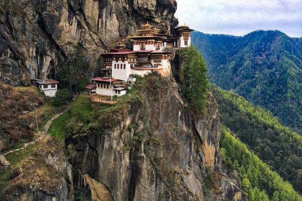 Paisaje de las montañas del Himalaya en Bután con un monasterio tradicional, ilustrando la logística de expediciones culturales.