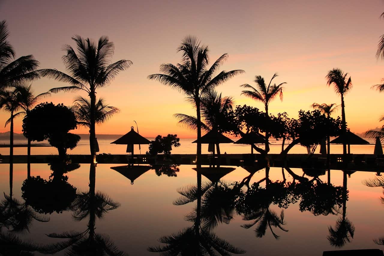 Piscina infinita al borde de una playa tropical en Bali al atardecer