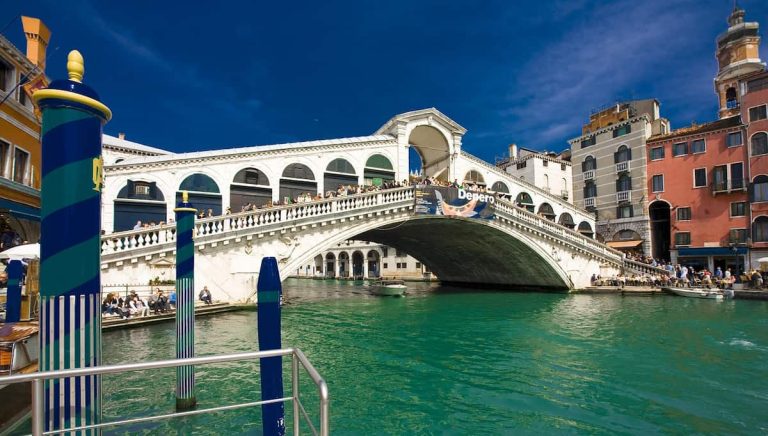 Puente de Rialto en Venecia al amanecer, con góndolas y edificios históricos