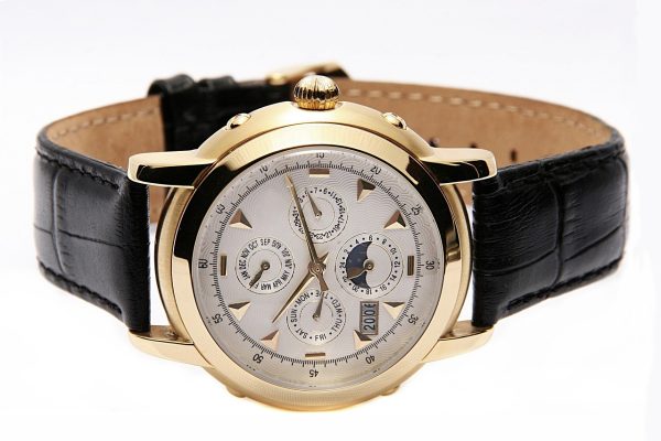 Reloj suizo de lujo con caja de oro y correa de cuero marrón sobre fondo neutro