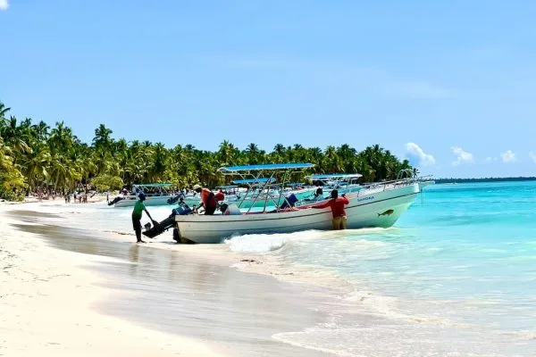 Barca a motor con pasajeros llegando a una playa de arena blanca en un viaje de lujo a República Dominicana