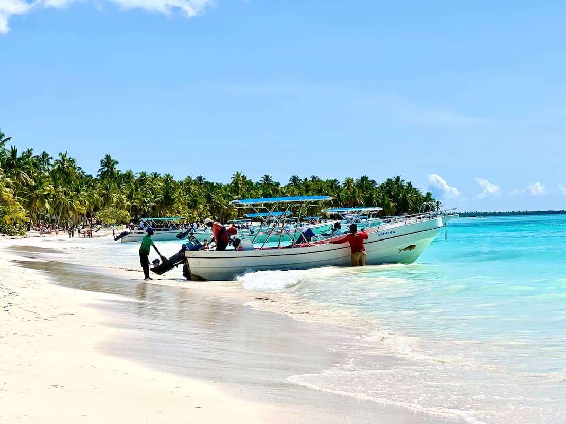 Barca a motor con pasajeros llegando a una playa de arena blanca en un viaje de lujo a República Dominicana