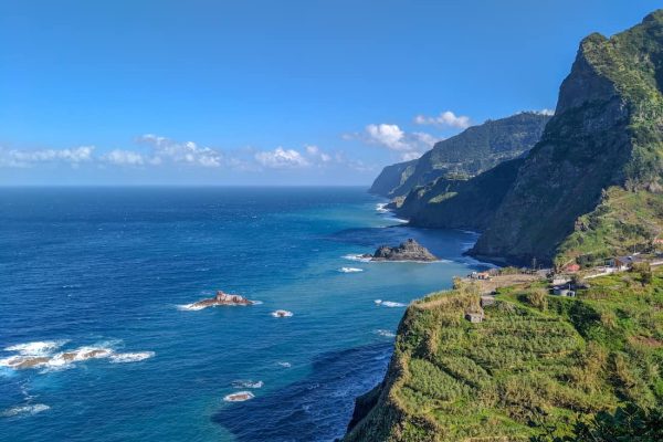 Vista panorámica de los acantilados verticales y la costa accidentada de Madeira bajo una luz cinematográfica.