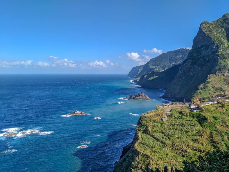 Vista panorámica de los acantilados verticales y la costa accidentada de Madeira bajo una luz cinematográfica.