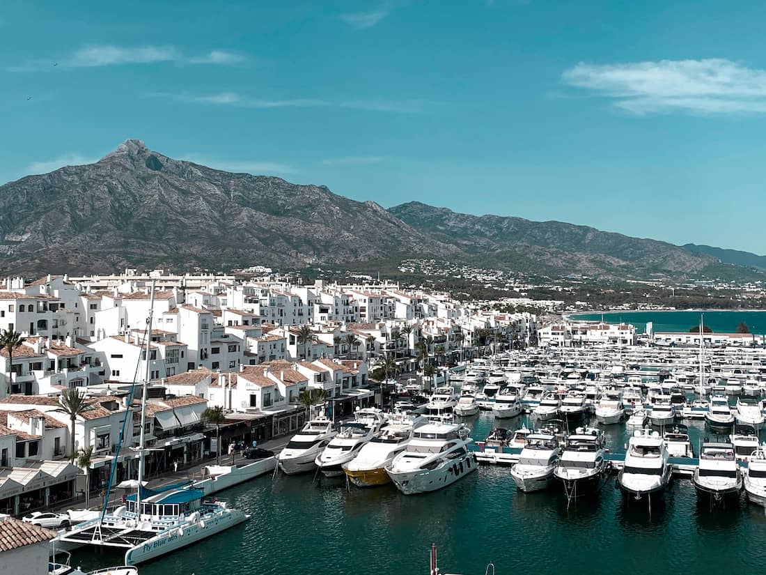 Vista aérea de Puerto Banús al atardecer con yates de lujo y palmeras