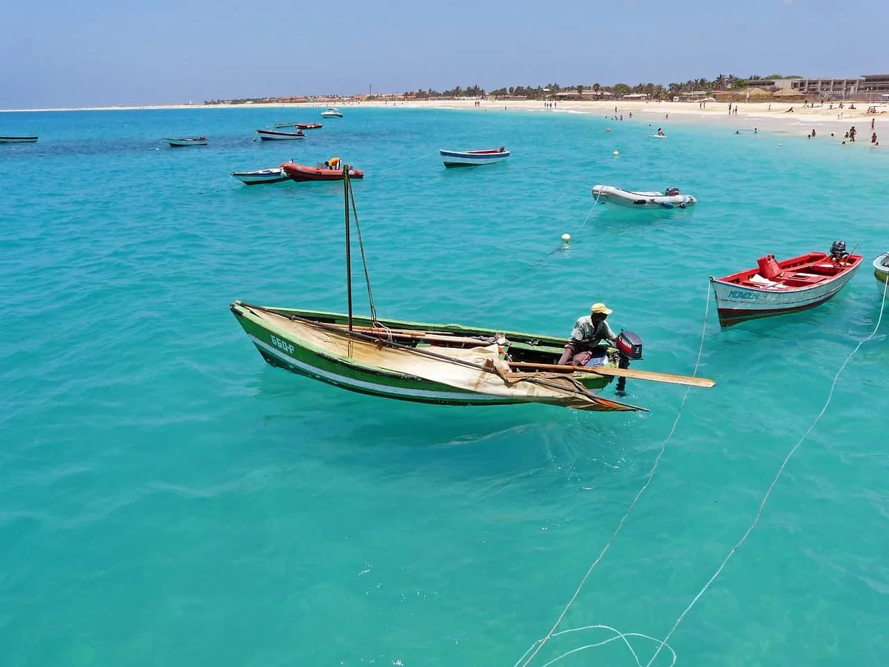 Barcas tradicionales fondeadas en mar transparente frente a playa virgen de arena blanca en viaje exclusivo Cabo Verde