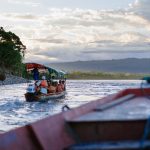 Barca con turistas navegando por el río Amazonas guiada por un guía con motor fuera de borda entre la selva