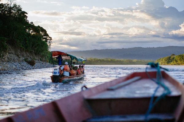 Barca con turistas navegando por el río Amazonas guiada por un guía con motor fuera de borda entre la selva