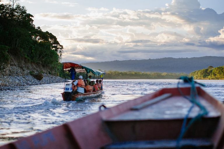 Barca con turistas navegando por el río Amazonas guiada por un guía con motor fuera de borda entre la selva