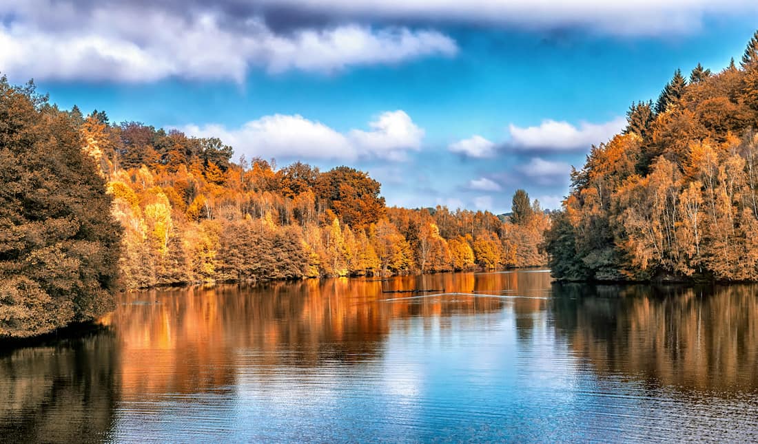 Paisaje otoñal de Charlevoix con bosques de arce rojos y dorados sobre el estuario del río San Lorenzo