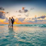 Pareja vestida de novios corriendo en una playa al borde del agua durante el atardecer en Isla Mauricio
