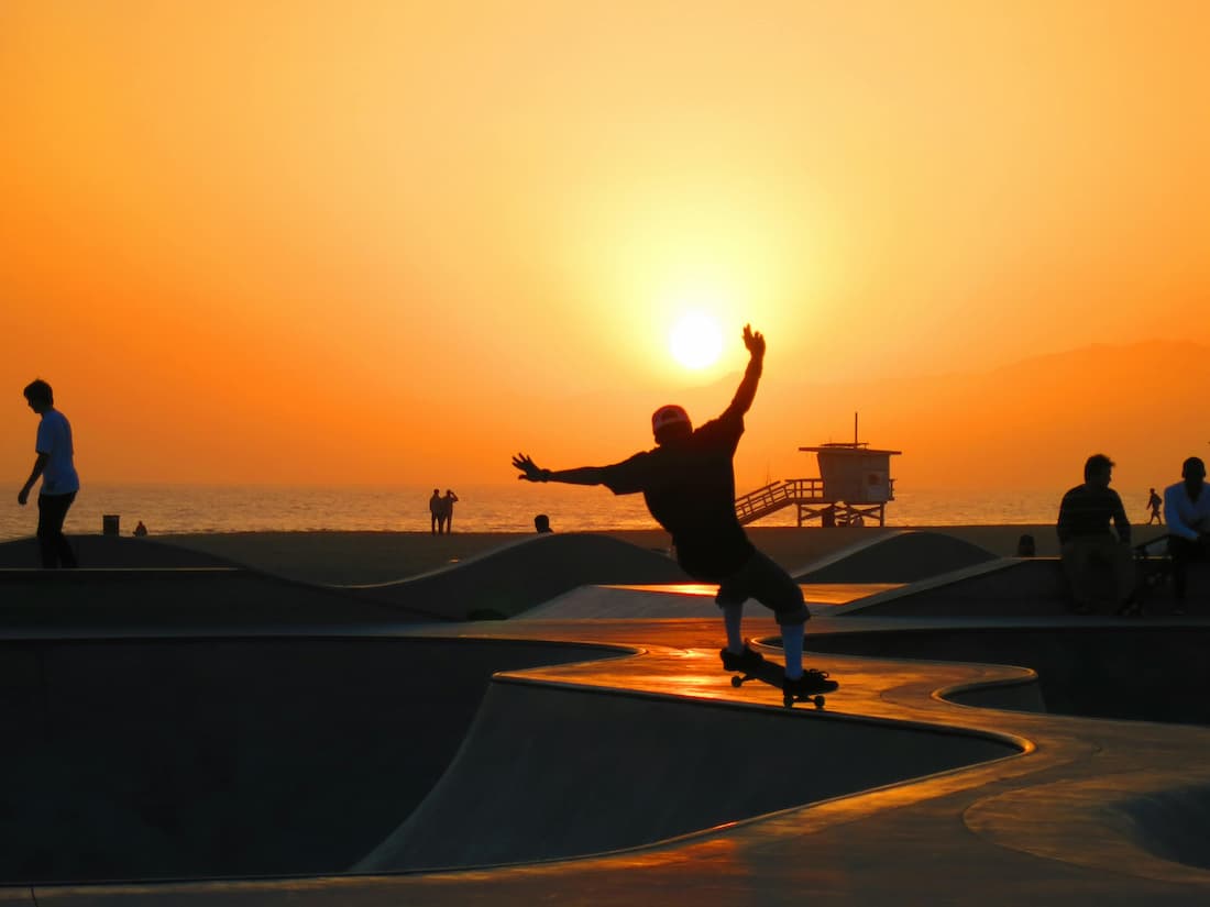 Paseo marítimo de Venice Beach al atardecer con artistas callejeros en Los Ángeles