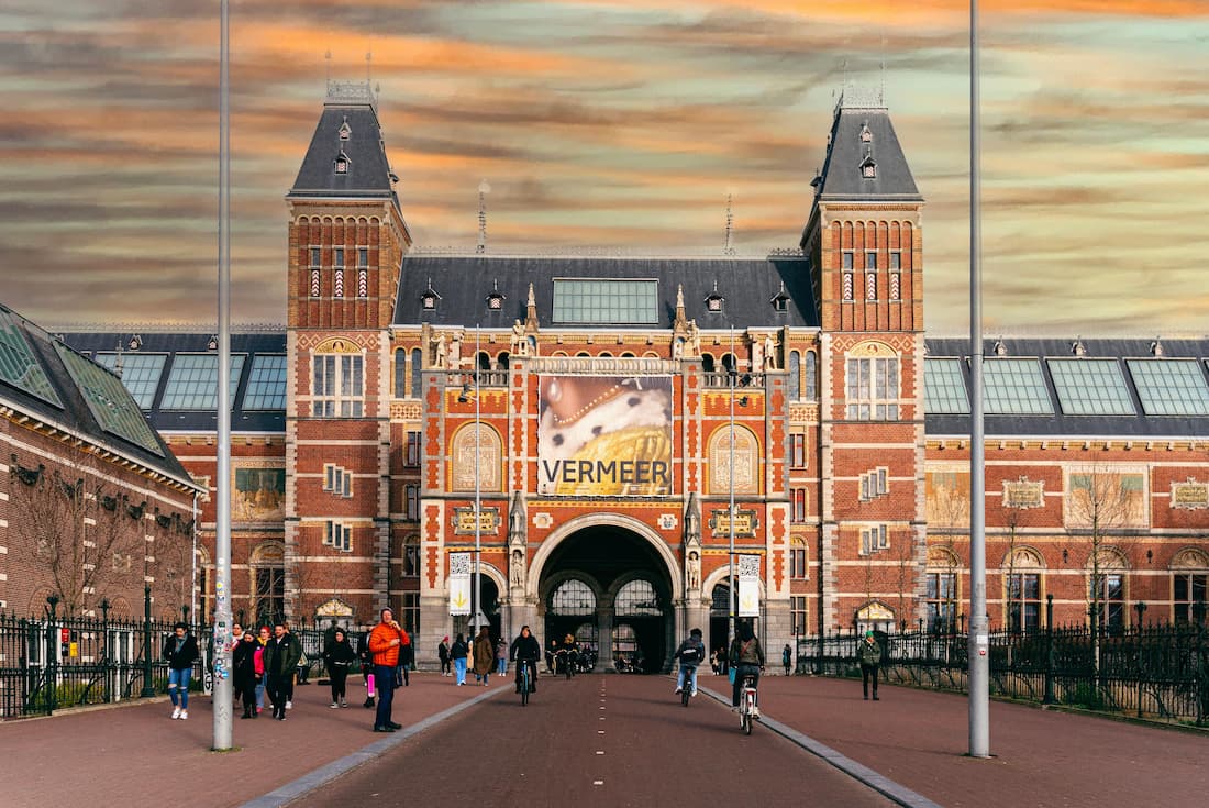 Fachada principal del Rijksmuseum de Ámsterdam al atardecer con reflejo en el estanque del Museumplein