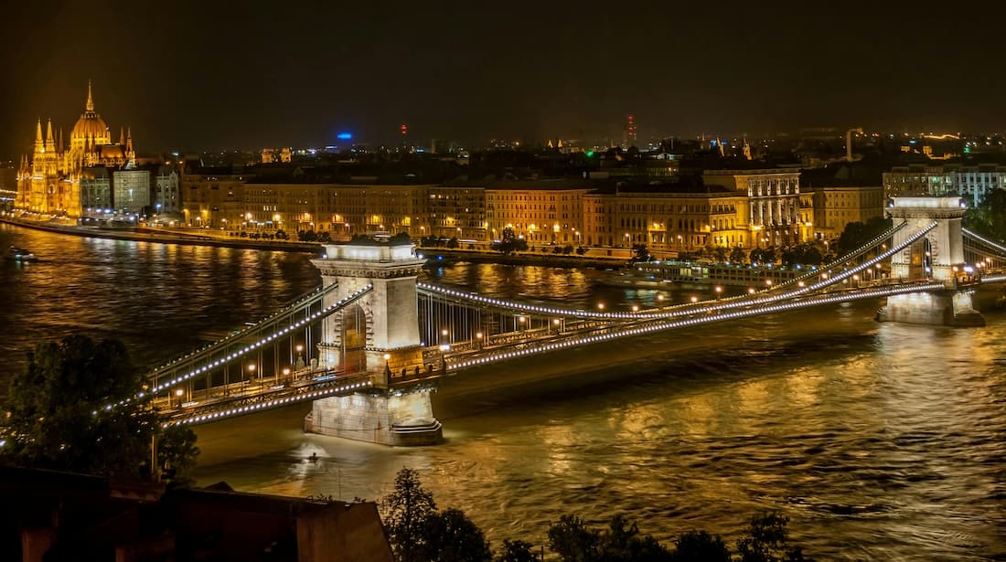Puente de las Cadenas de Budapest iluminado de noche sobre el Danubio con el Castillo de Buda al fondo