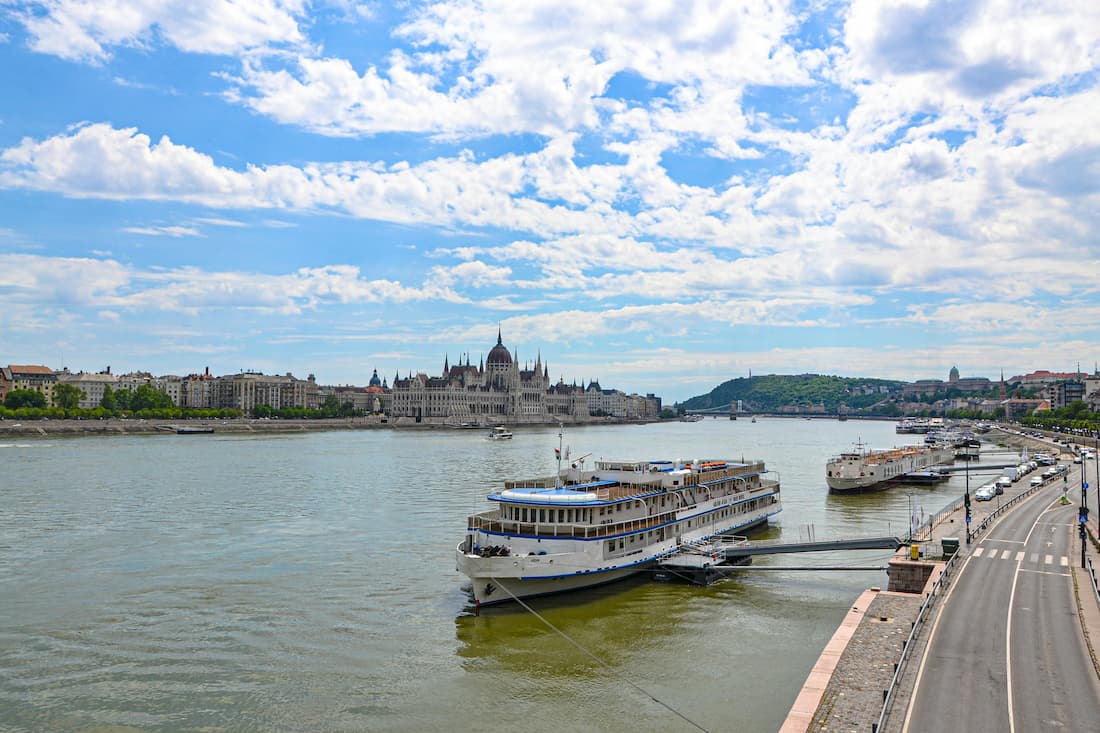 Crucero fluvial navegando por el Danubio al amanecer con ciudad histórica europea iluminada al fondo