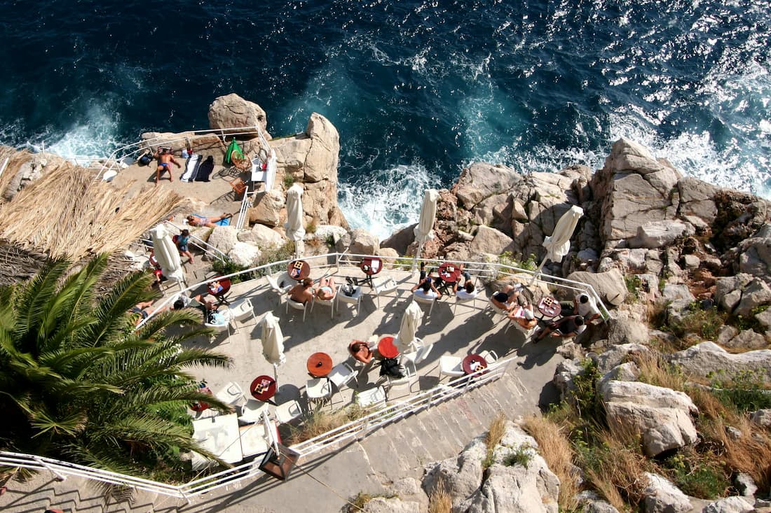 Terraza de restaurante en Dubrovnik con vistas al mar Adriático y las murallas de la Ciudad Vieja al fondo