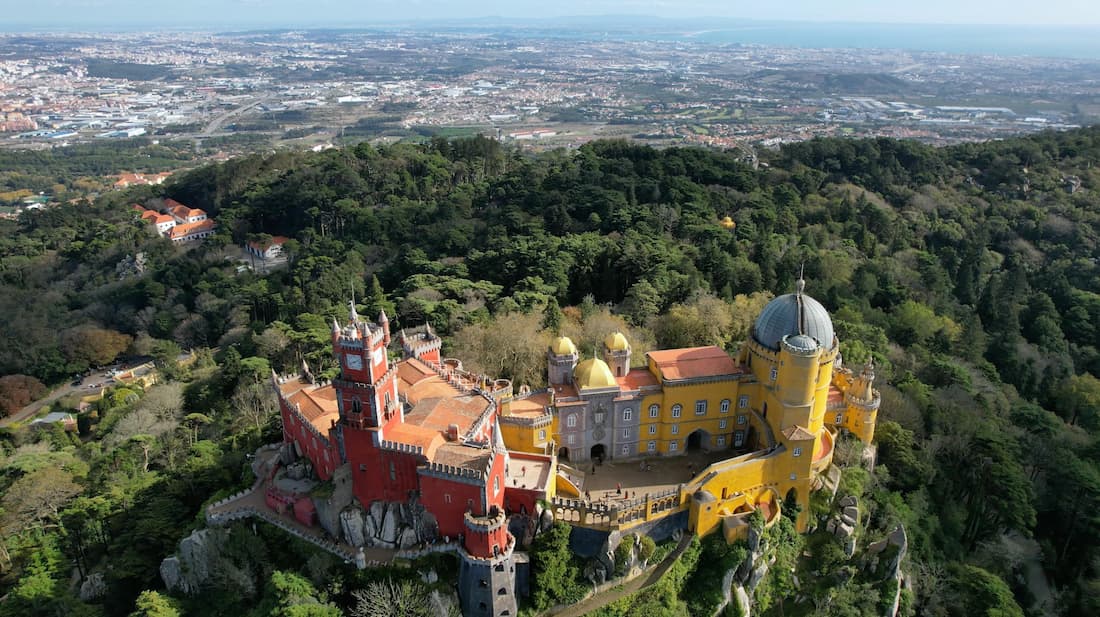 Palácio da Pena de Sintra con sus colores amarillos y rojos sobre la sierra en una excursión desde Lisboa