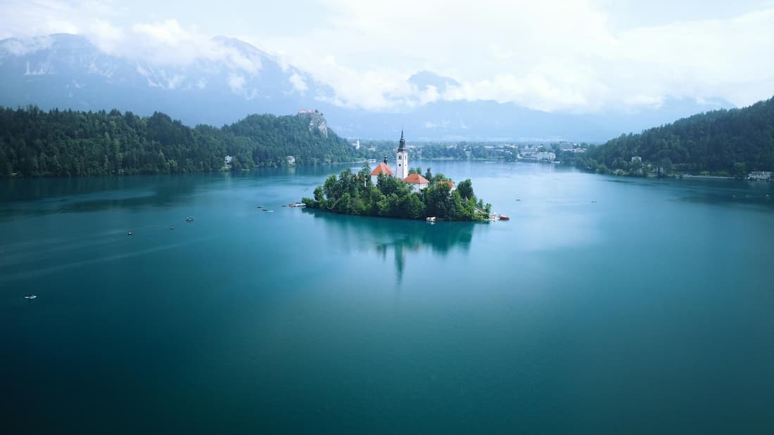 Lago Bled con la isla y su iglesia blanca, el castillo sobre el acantilado y los Alpes Julianos nevados al fondo en Eslovenia