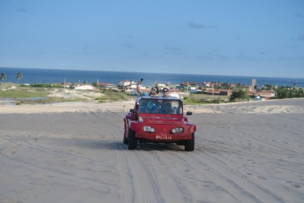 Mehari rojo sobre las dunas de Natal Brasil con el mar Atlántico al fondo