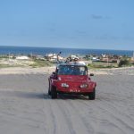 Mehari rojo sobre las dunas de Natal Brasil con el mar Atlántico al fondo