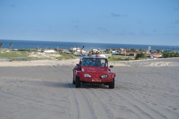 Mehari rojo sobre las dunas de Natal Brasil con el mar Atlántico al fondo