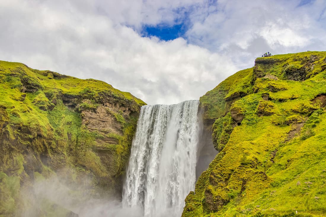 Cascada Skógafoss en la Costa Sur de Islandia con su cortina de agua y el arcoíris permanente en excursión desde Reikiavik