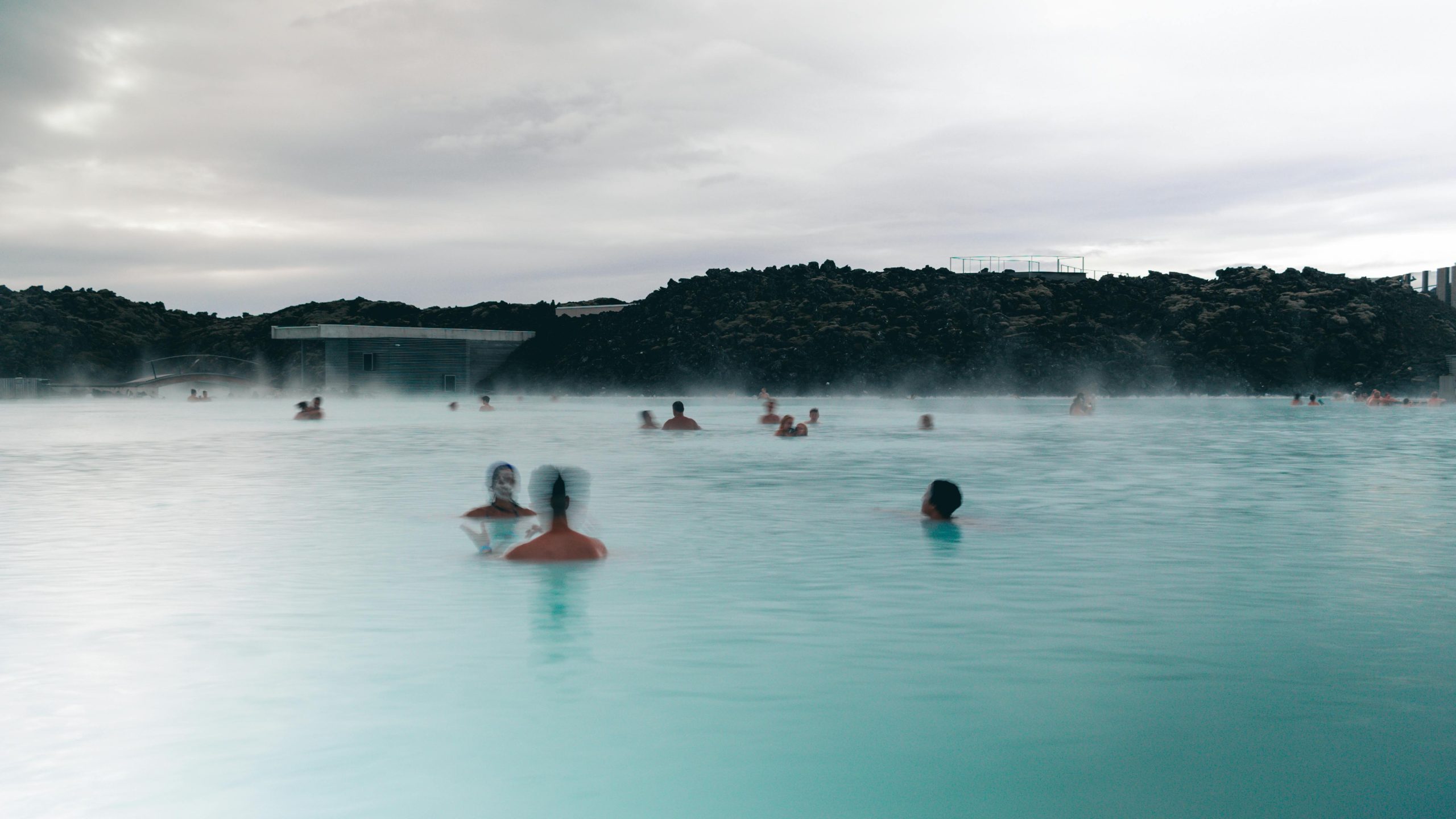Bañistas en la Laguna Azul de Islandia con sus aguas turquesas y el vapor geotérmico al atardecer cerca de Reikiavik