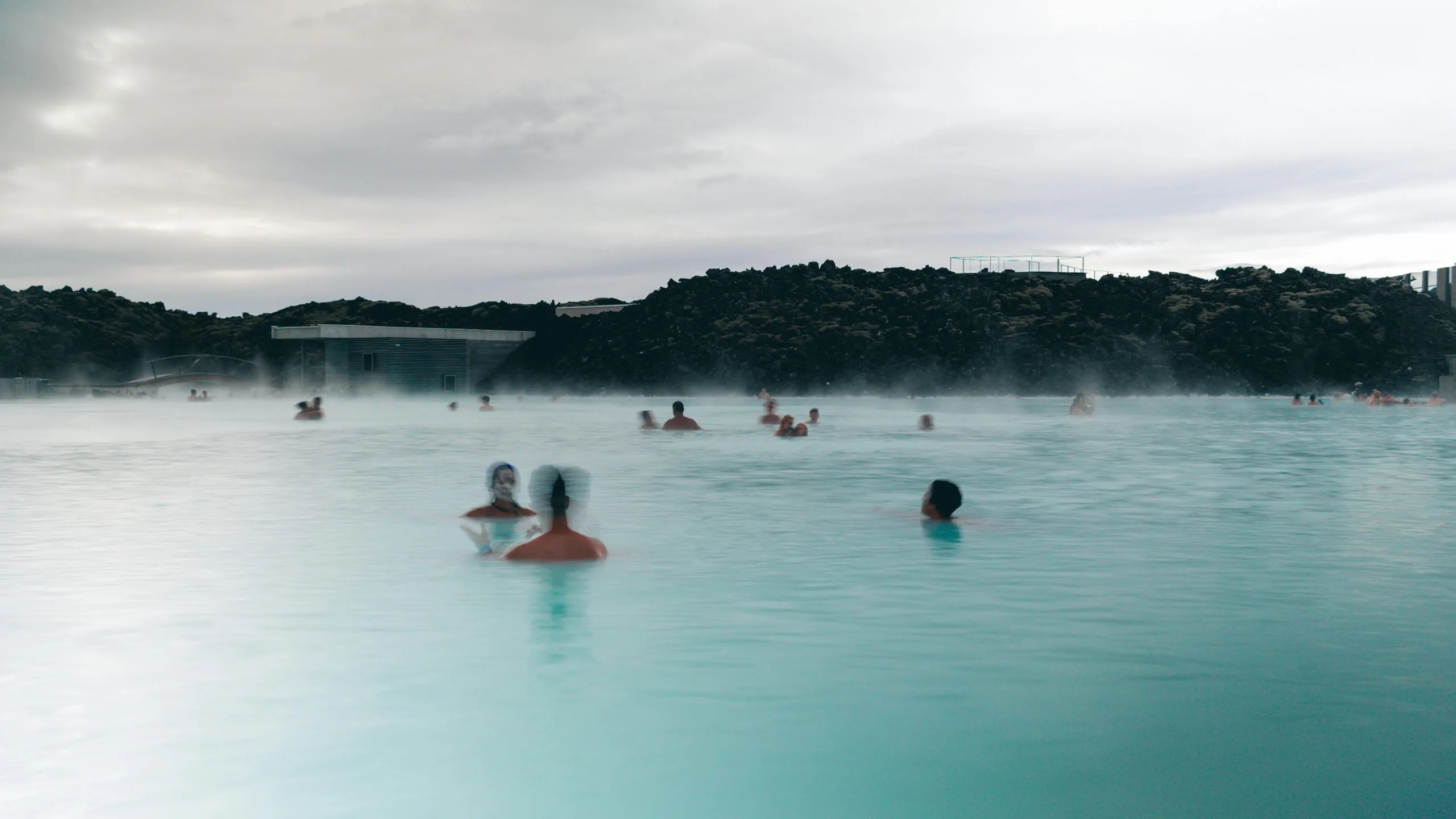 Bañistas en la Laguna Azul de Islandia con sus aguas turquesas y el vapor geotérmico al atardecer cerca de Reikiavik